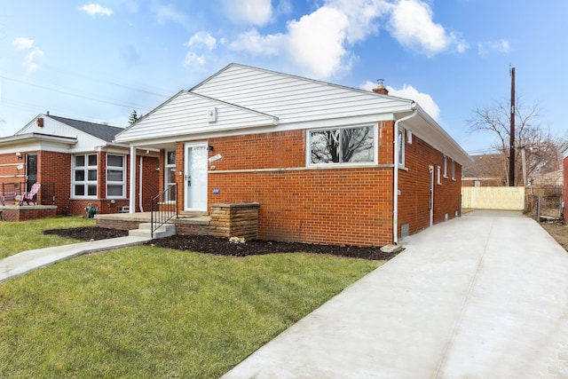 bungalow-style home with a front yard, concrete driveway, brick siding, and fence