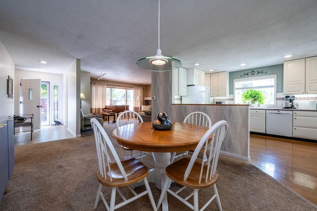 dining space with a textured ceiling, carpet flooring, wood finished floors, and recessed lighting