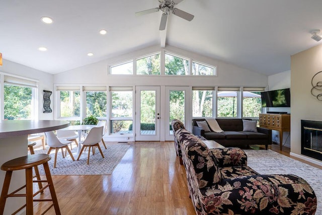 living area with light wood-type flooring, a glass covered fireplace, vaulted ceiling with beams, and recessed lighting