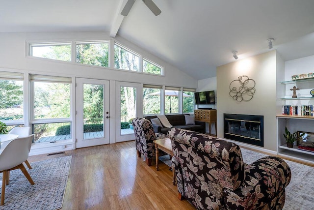 living area featuring a wealth of natural light, a glass covered fireplace, visible vents, and wood finished floors