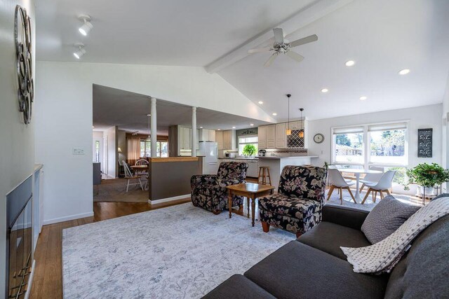 living room with vaulted ceiling with beams, ceiling fan, wood finished floors, and a healthy amount of sunlight