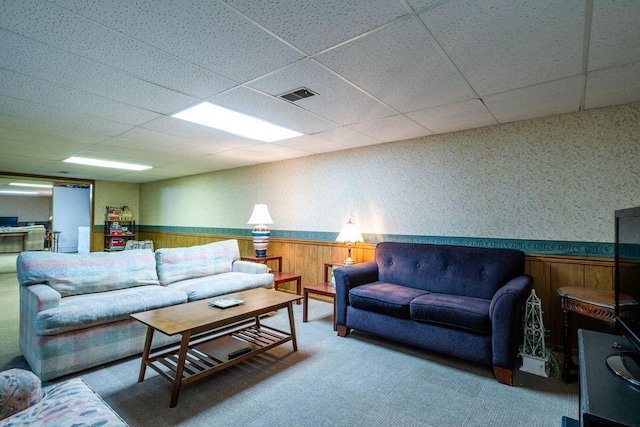 living area with a drop ceiling, wainscoting, visible vents, and wallpapered walls