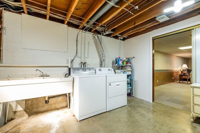 laundry area featuring concrete block wall, laundry area, wainscoting, washer and dryer, and a sink