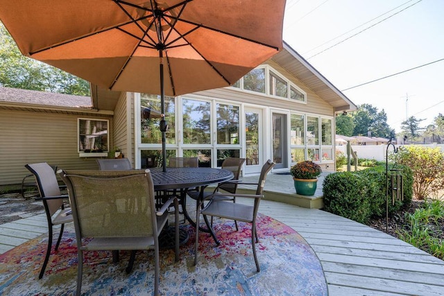 wooden terrace with outdoor dining space and a sunroom