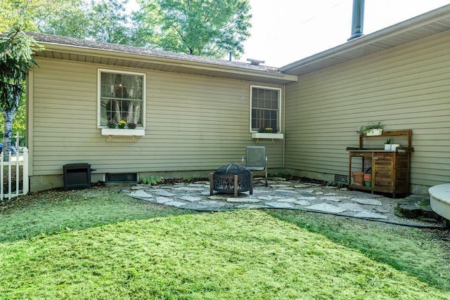 back of property featuring a patio area, a fire pit, and a lawn