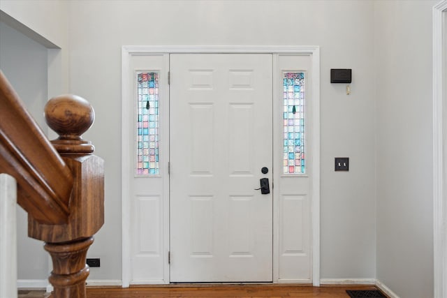 entryway with stairs, wood finished floors, and baseboards