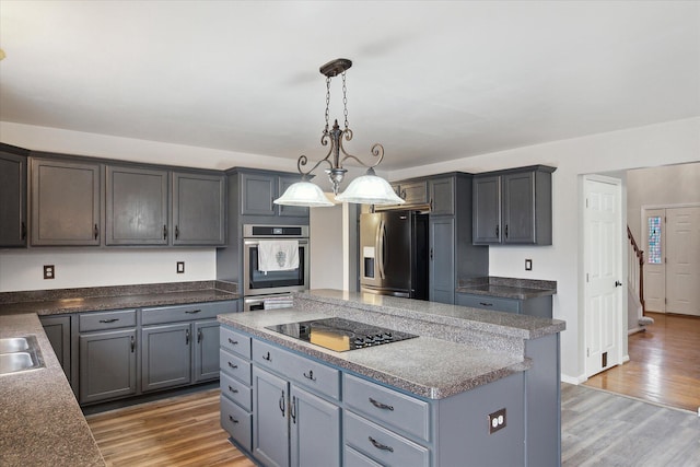 kitchen featuring light wood-style flooring, a kitchen island, fridge with ice dispenser, oven, and black electric cooktop