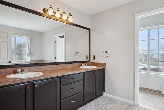 bathroom with double vanity, tile patterned flooring, baseboards, and a sink