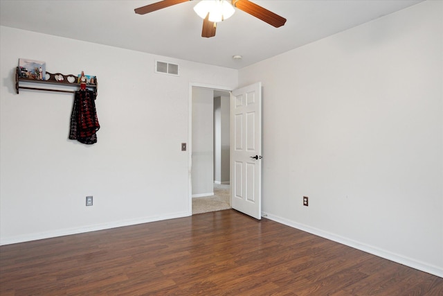 unfurnished room with visible vents, dark wood finished floors, baseboards, and ceiling fan