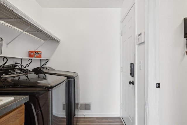 clothes washing area with washing machine and clothes dryer, visible vents, wood finished floors, laundry area, and baseboards