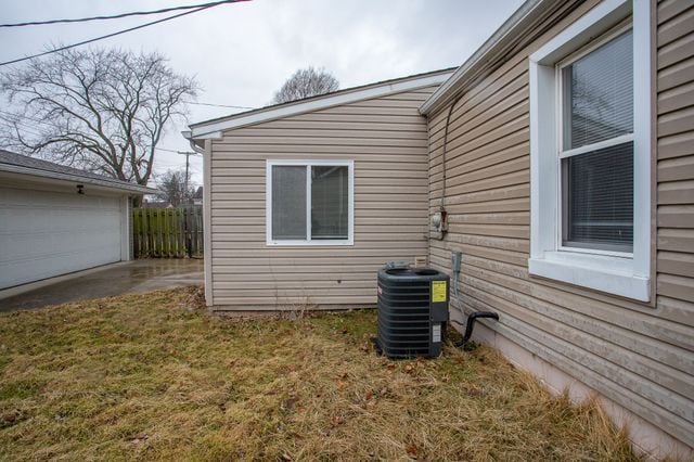 view of side of home with a garage, central AC, a yard, and fence