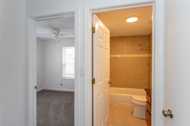 bathroom with toilet, a ceiling fan, baseboards, shower / washtub combination, and tile patterned floors