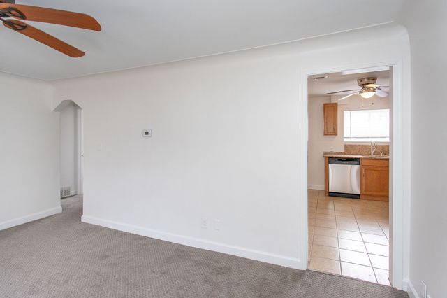 spare room featuring a ceiling fan, light carpet, baseboards, and light tile patterned flooring