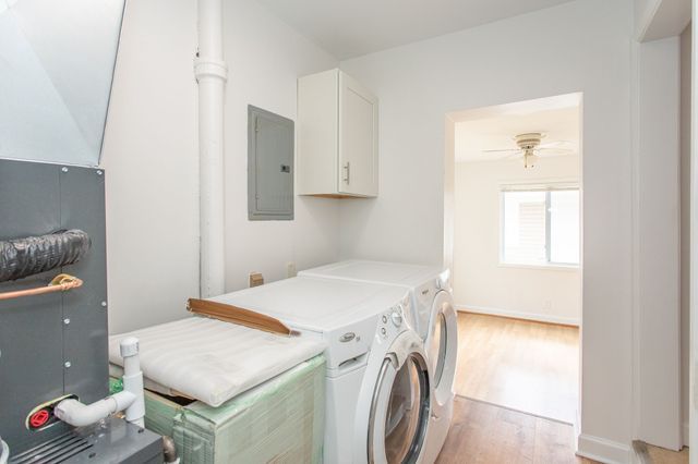 laundry room with ceiling fan, independent washer and dryer, light wood-type flooring, cabinet space, and electric panel