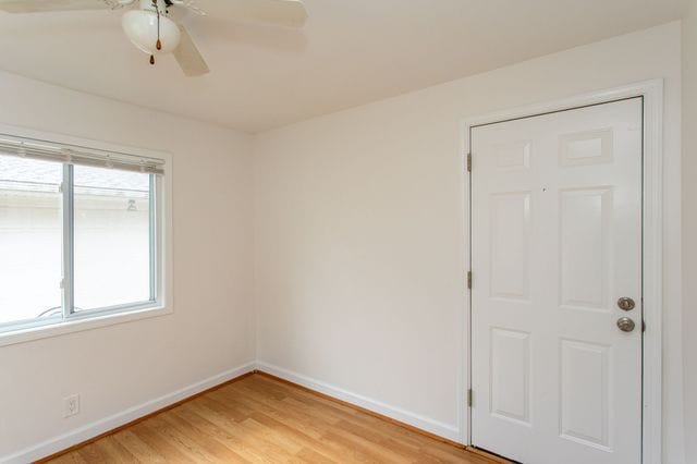 unfurnished room featuring ceiling fan, light wood finished floors, and baseboards