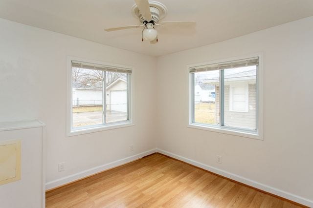 spare room featuring baseboards, ceiling fan, a wealth of natural light, and light wood-style floors