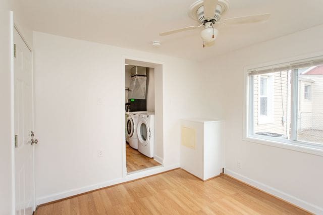 interior space featuring light wood-style floors, ceiling fan, baseboards, and washer and clothes dryer