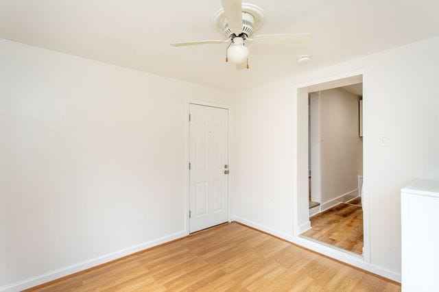 spare room featuring light wood finished floors, ceiling fan, baseboards, and washer / clothes dryer