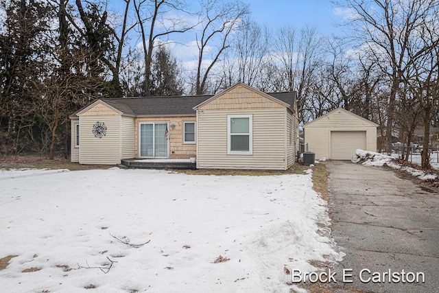 bungalow-style home featuring a garage, central AC, an outdoor structure, and aphalt driveway