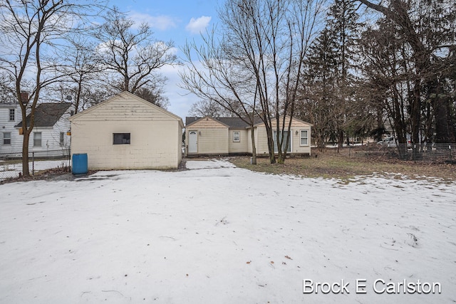 snow covered rear of property with an outbuilding and fence