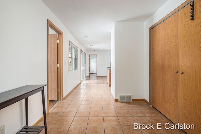 hall featuring light tile patterned floors, visible vents, and baseboards