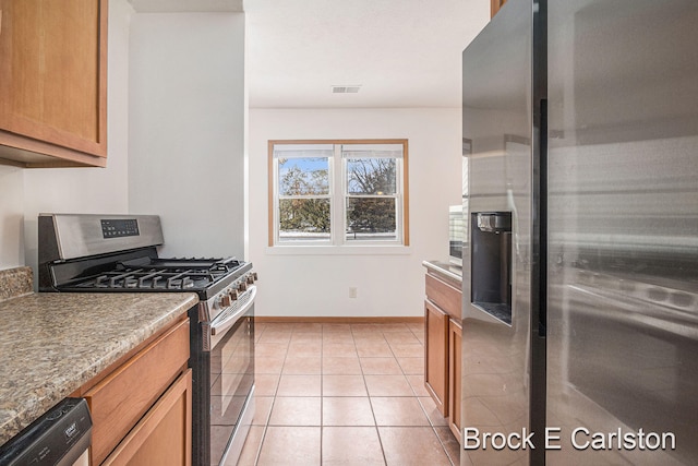 kitchen featuring light tile patterned floors, stainless steel appliances, visible vents, baseboards, and brown cabinetry