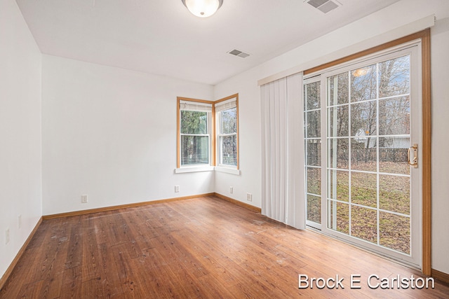 unfurnished room with hardwood / wood-style flooring, baseboards, and visible vents