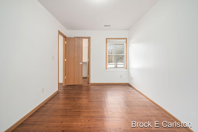 empty room with baseboards, visible vents, and wood finished floors