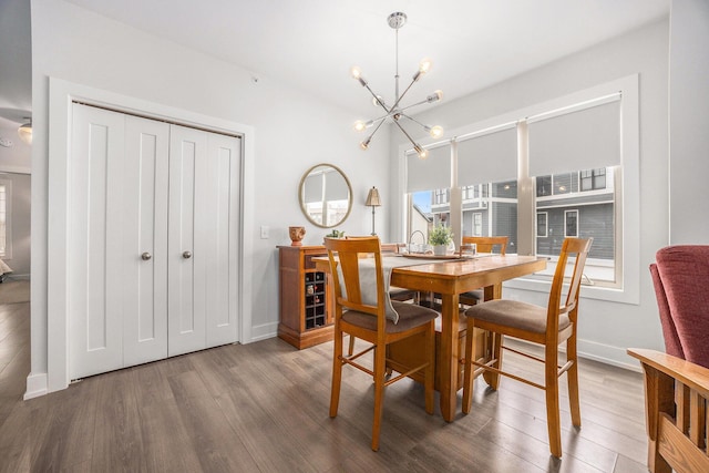 dining area with baseboards, wood finished floors, and a notable chandelier