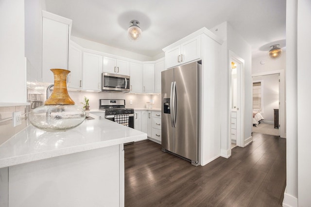 kitchen featuring baseboards, dark wood-style floors, appliances with stainless steel finishes, white cabinetry, and backsplash