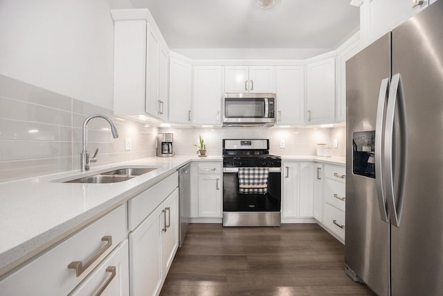 kitchen featuring dark wood finished floors, backsplash, appliances with stainless steel finishes, white cabinetry, and a sink