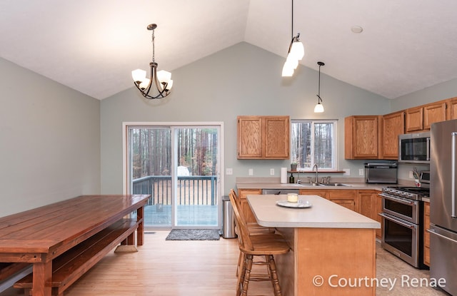 kitchen featuring stainless steel appliances, light countertops, light wood-style flooring, a sink, and a kitchen island