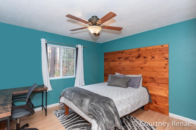 bedroom featuring ceiling fan, a textured ceiling, wood finished floors, and baseboards