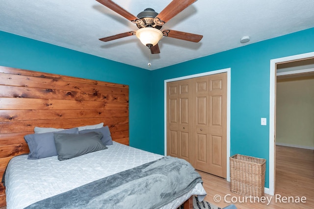 bedroom with a closet, ceiling fan, a textured ceiling, wood finished floors, and baseboards