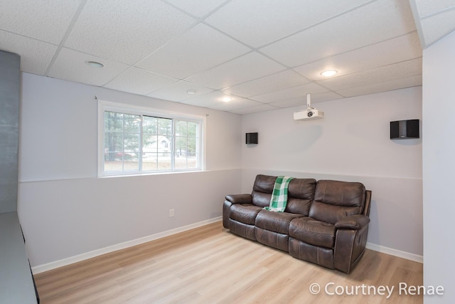 living area featuring baseboards, a drop ceiling, and wood finished floors