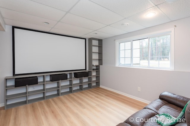 home theater room with wood finished floors, a paneled ceiling, and baseboards