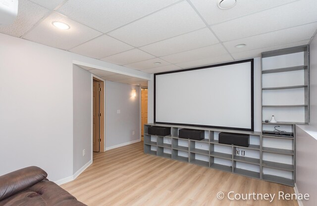 home theater featuring a drop ceiling, baseboards, and wood finished floors