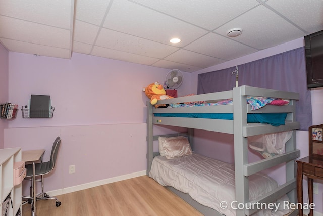 bedroom with a paneled ceiling, baseboards, and wood finished floors