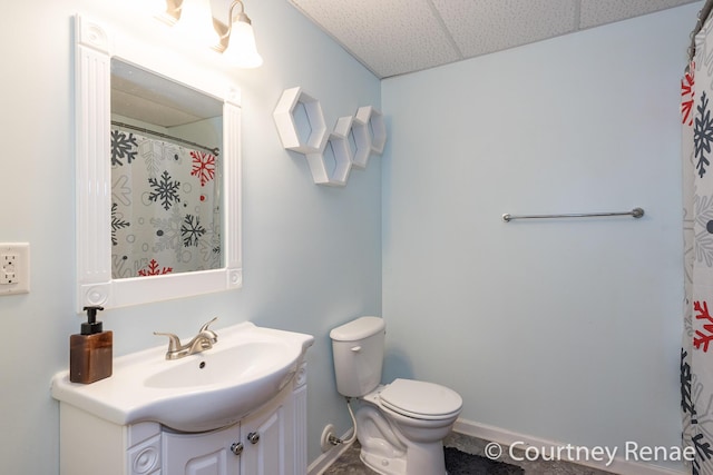 full bath with a paneled ceiling, curtained shower, toilet, vanity, and baseboards