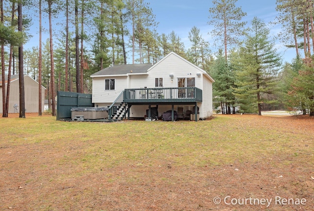 back of house featuring a lawn, a wooden deck, and a hot tub