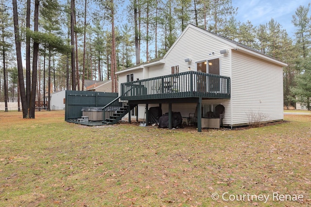 rear view of property featuring a lawn, a wooden deck, and a hot tub