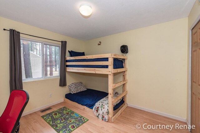 bedroom with baseboards, visible vents, and wood finished floors