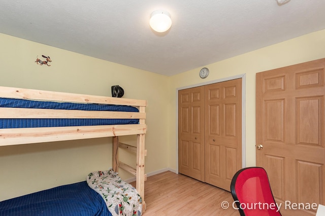 bedroom featuring light wood finished floors, baseboards, and a textured ceiling