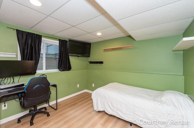 bedroom with recessed lighting, wood finished floors, a paneled ceiling, and baseboards