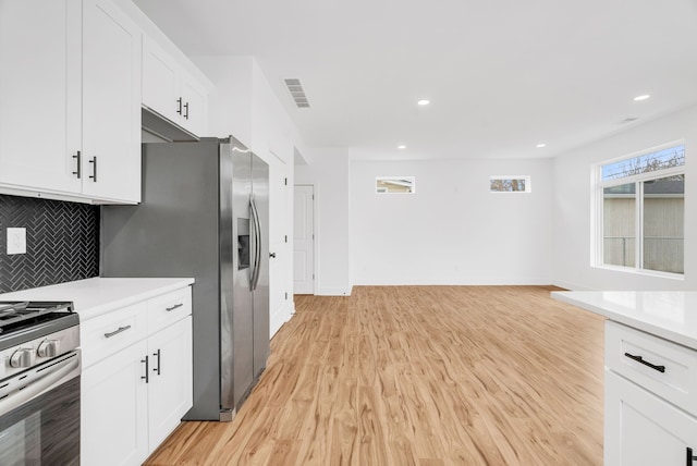 kitchen featuring stainless steel appliances, light countertops, visible vents, and light wood finished floors