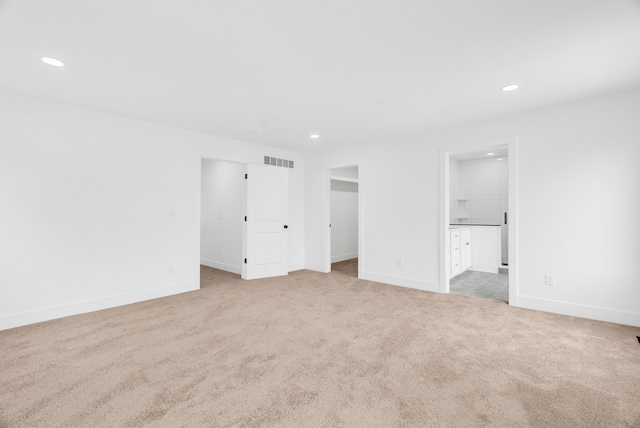 unfurnished bedroom with carpet, visible vents, a walk in closet, and recessed lighting