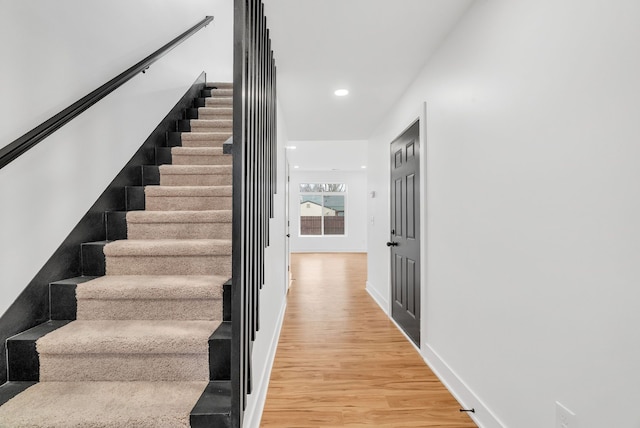 stairs featuring baseboards, wood finished floors, and recessed lighting