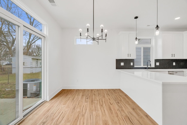 kitchen featuring visible vents, white cabinetry, baseboards, light wood finished floors, and tasteful backsplash