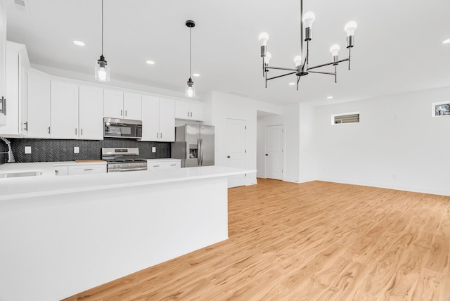 kitchen with stainless steel appliances, light wood-type flooring, backsplash, and light countertops