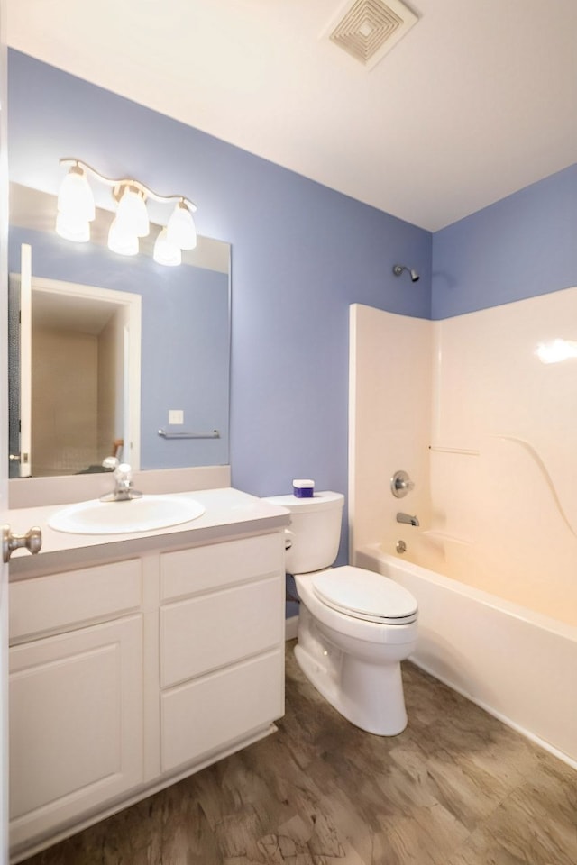 bathroom featuring toilet, wood finished floors, vanity, visible vents, and  shower combination